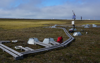 A field with wood slats in a path; Science instruments are in the grass